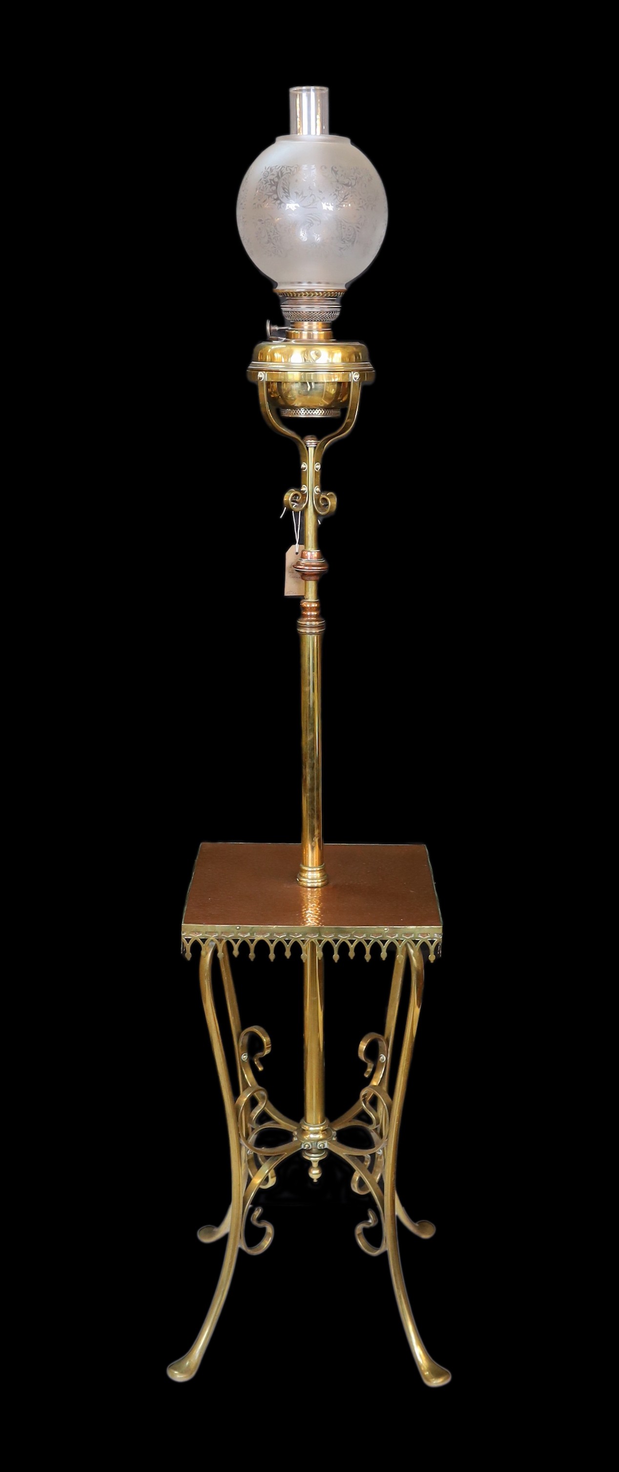 An Edwardian brass and copper telescopic oil lamp standard with scrolling underframe and etched glass globe, height 155cm. width 35cm